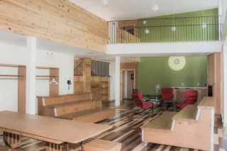Modern wooden common area with loft and red chairs