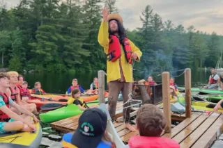 Animateur sur ponton entouré d’enfants en kayaks