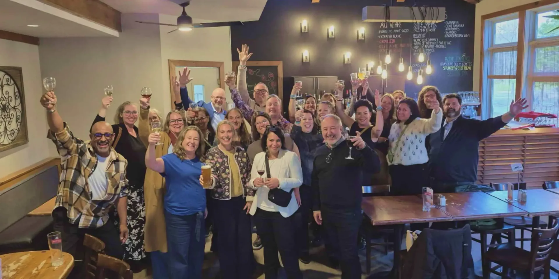 Group of colleagues toasting drinks inside cozy bar