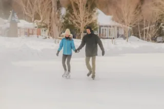 Couple patinant main dans la main en hiver
