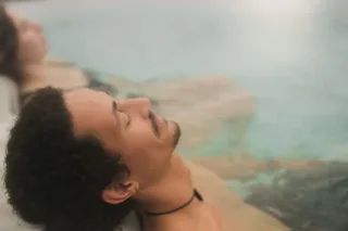 Homme se relaxant dans un bain thermal, femme derrière