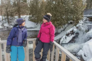 Deux femmes en tenue d’hiver près d’une cascade gelée