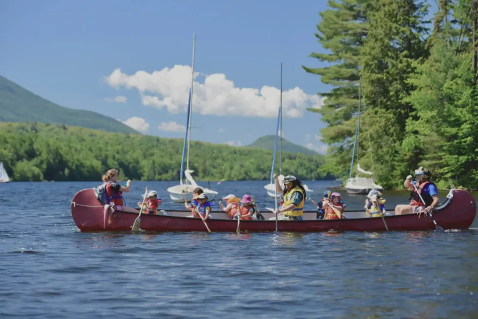 Enfants en canot sur lac entouré de montagnes