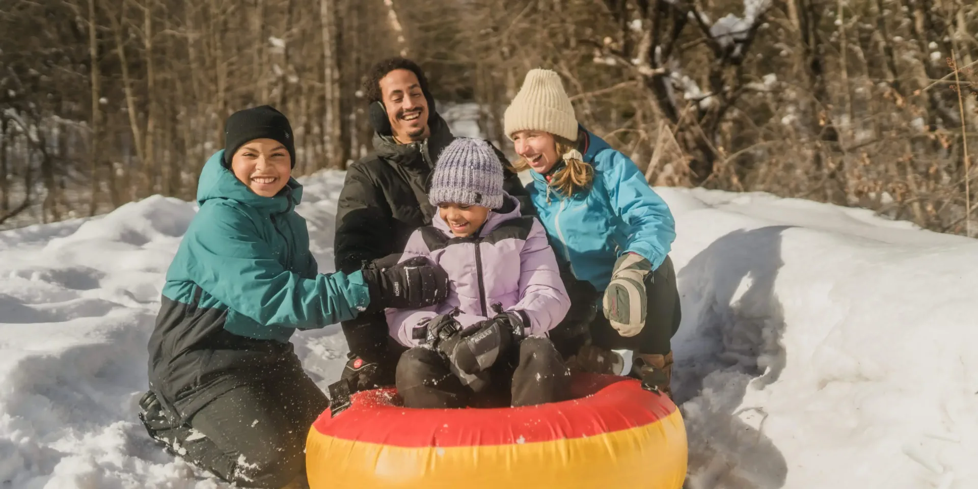 Famille faisant de la descente en tube sur neige en forêt