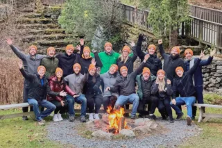 Group cheering around campfire wearing orange beanies