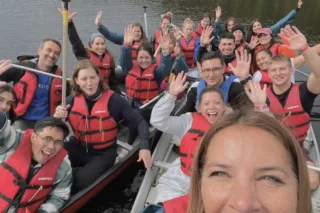 Group canoeing on lake wearing red life jackets