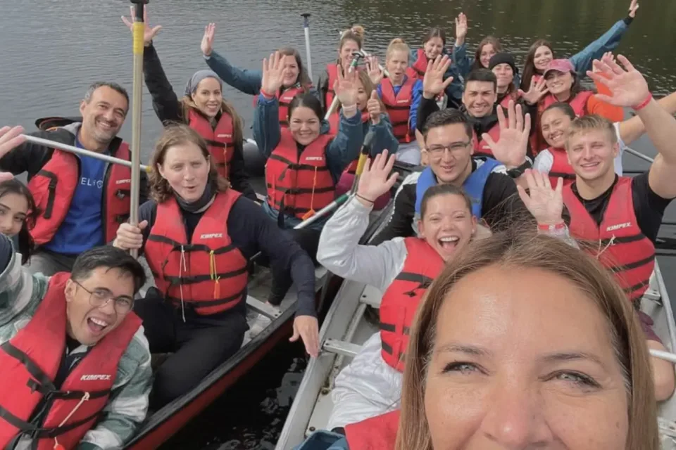 Group canoeing on lake wearing red life jackets