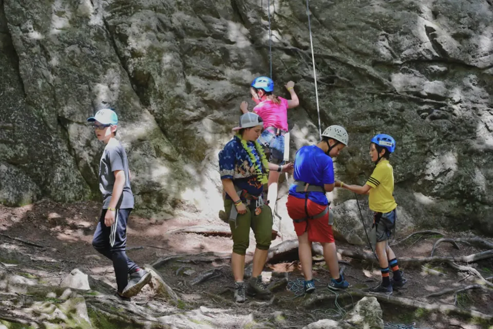 Enfants faisant de l’escalade en forêt, casques et cordes
