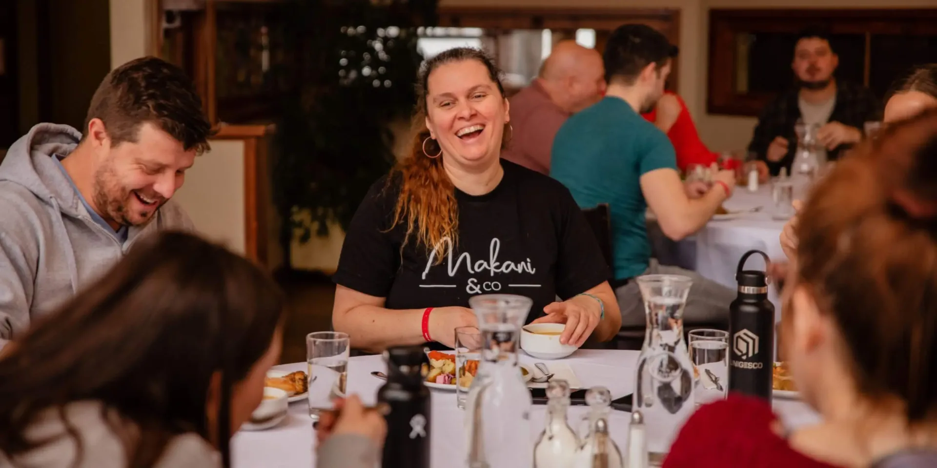 Friends laughing together at indoor dinner table