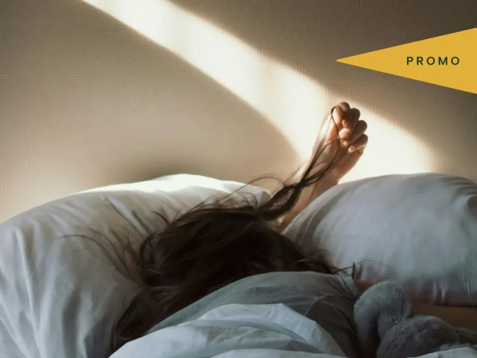 Person stretching in bed under morning light
