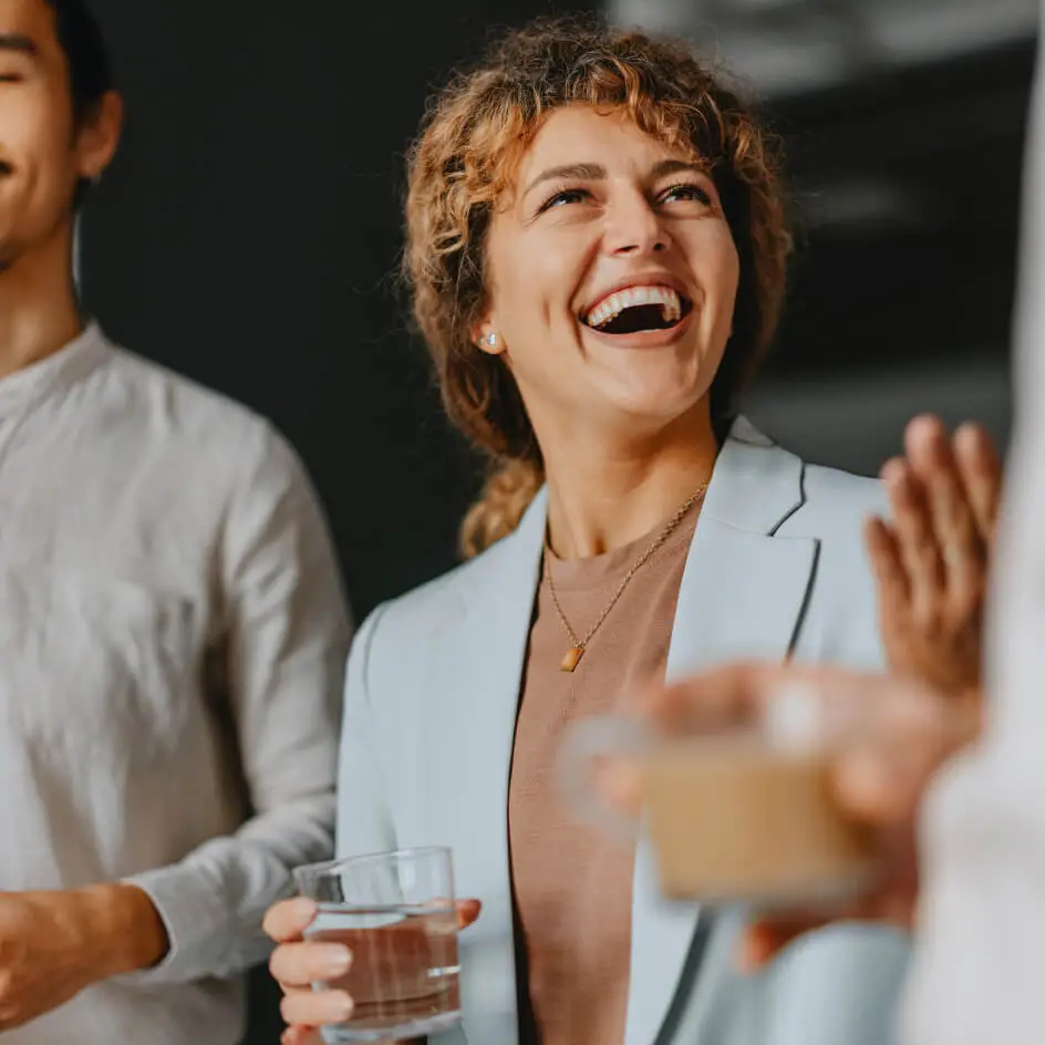 Smiling woman holding water glass in office conversation