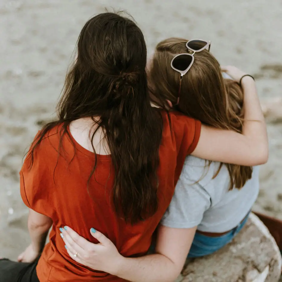 Two women sitting together with arms around