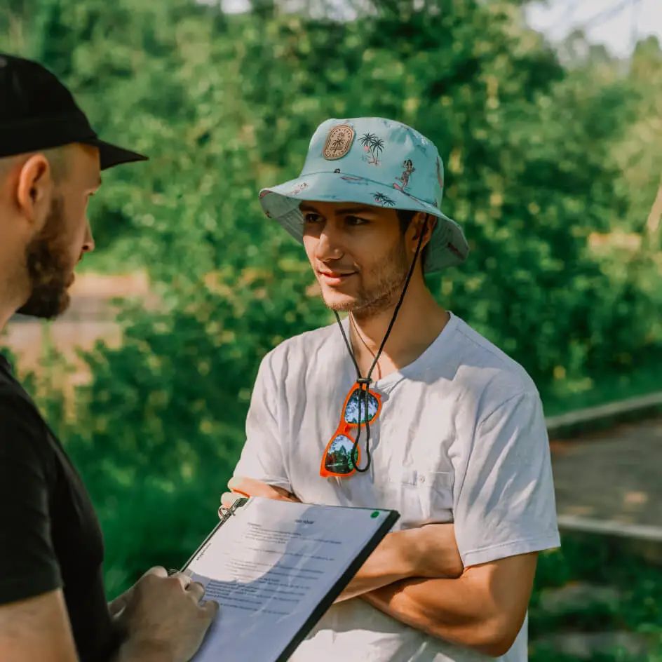 Man interviewed outdoors holding clipboard and notes
