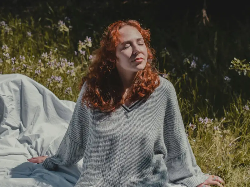 Femme rousse assise dans l’herbe au soleil