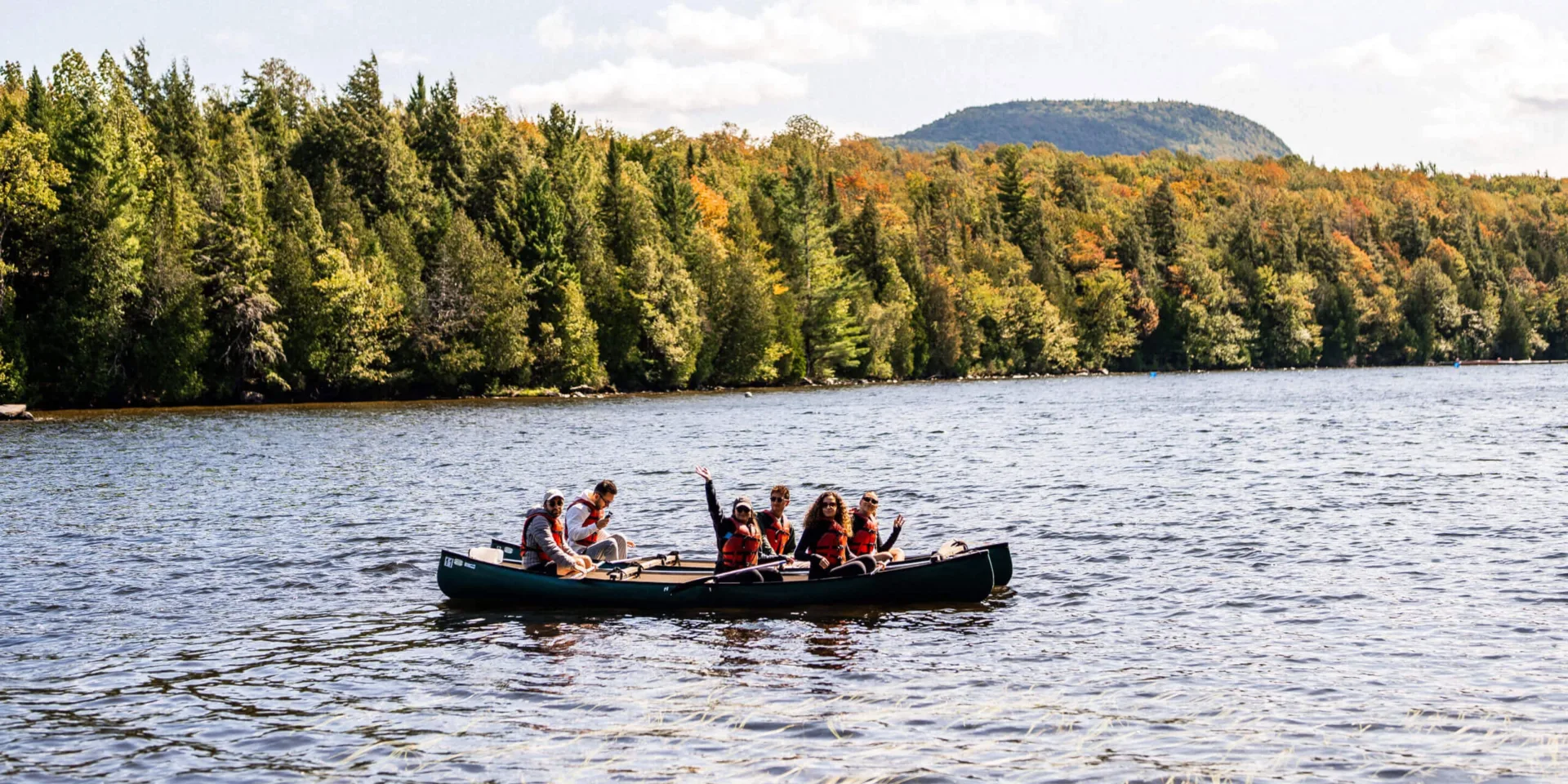 Group canoeing on lake with autumn forest backdrop