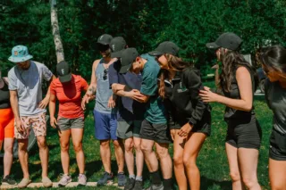 Team balancing on wooden plank outdoors