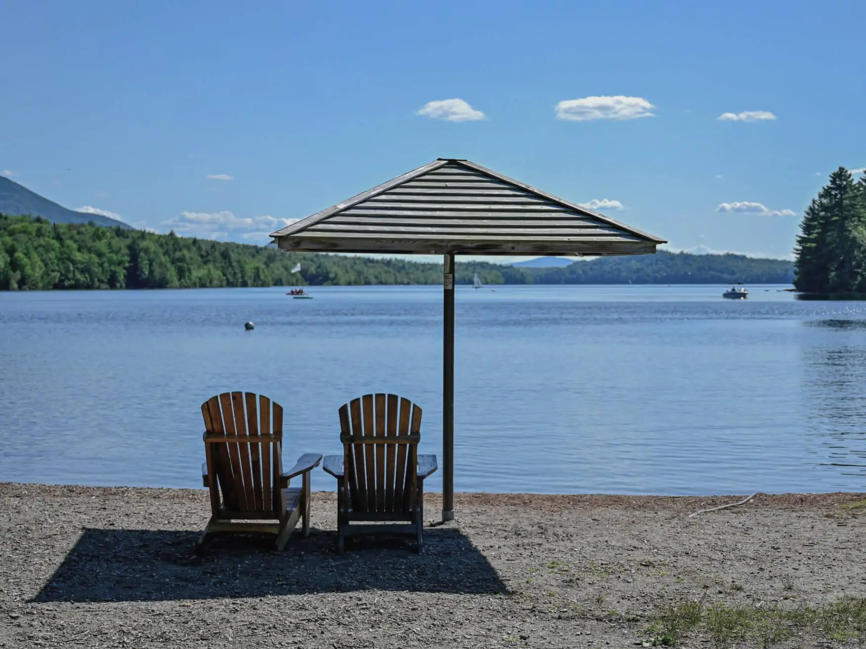 Deux chaises en bois sous parasol face au lac