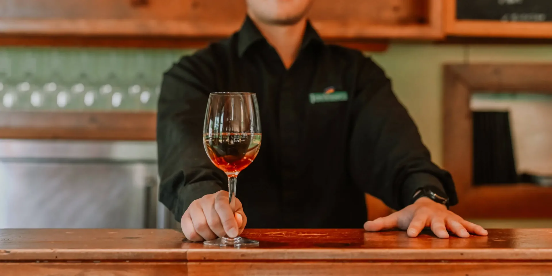 Serveur présentant un verre de vin rosé au bar