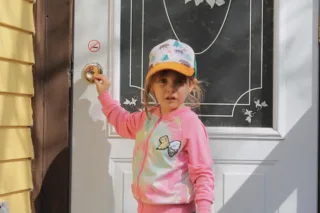 Child in colorful jacket holding front door knob