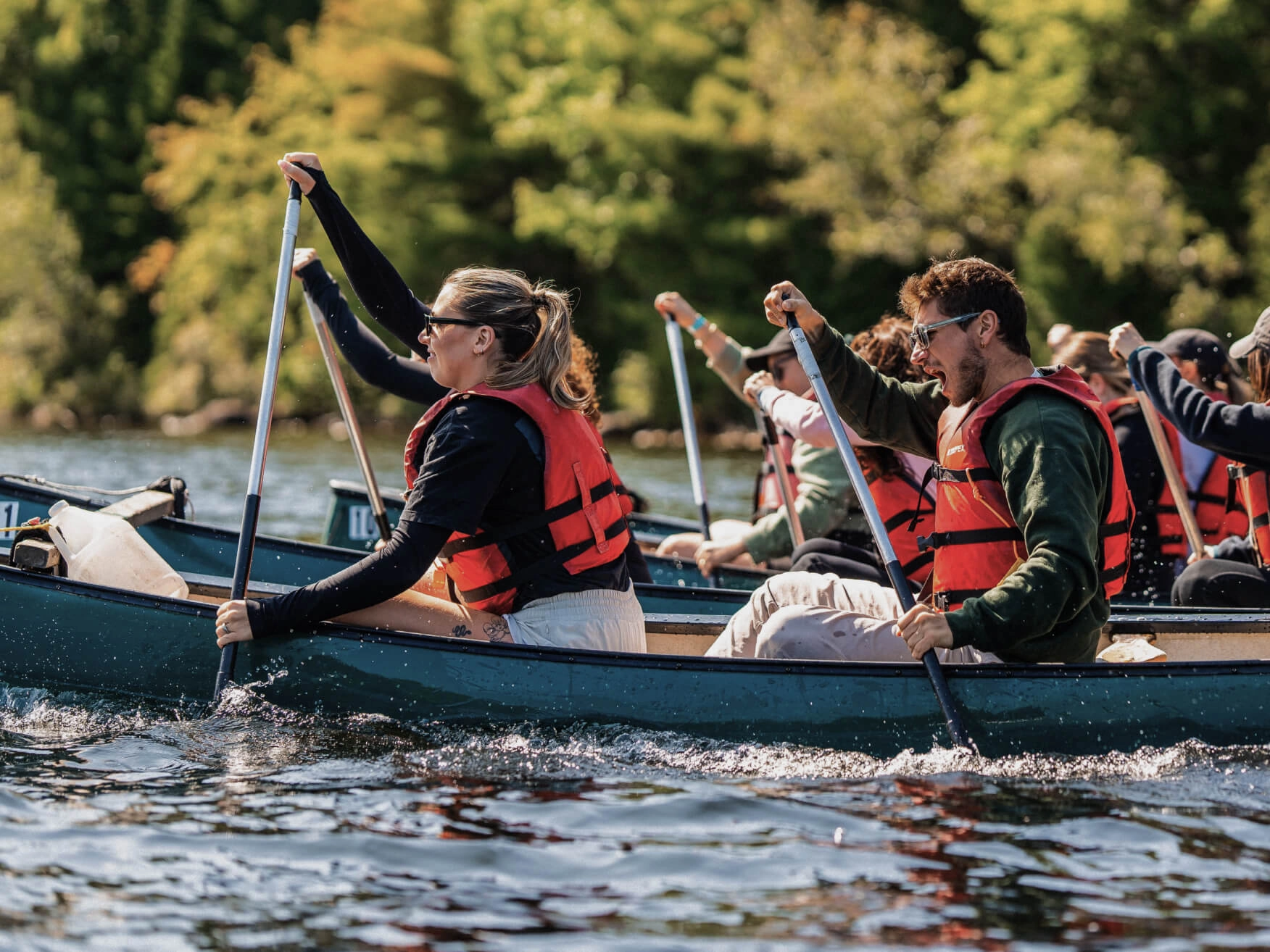 A group canoeing on a lake surrounded by a forest