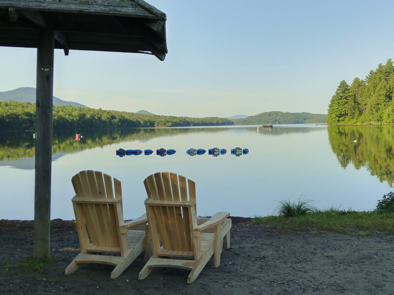 Deux chaises en bois face à un lac calme