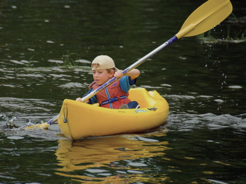 Enfant en kayak jaune sur lac calme