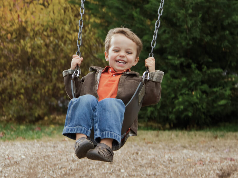 Jeune garçon souriant sur une balançoire au parc