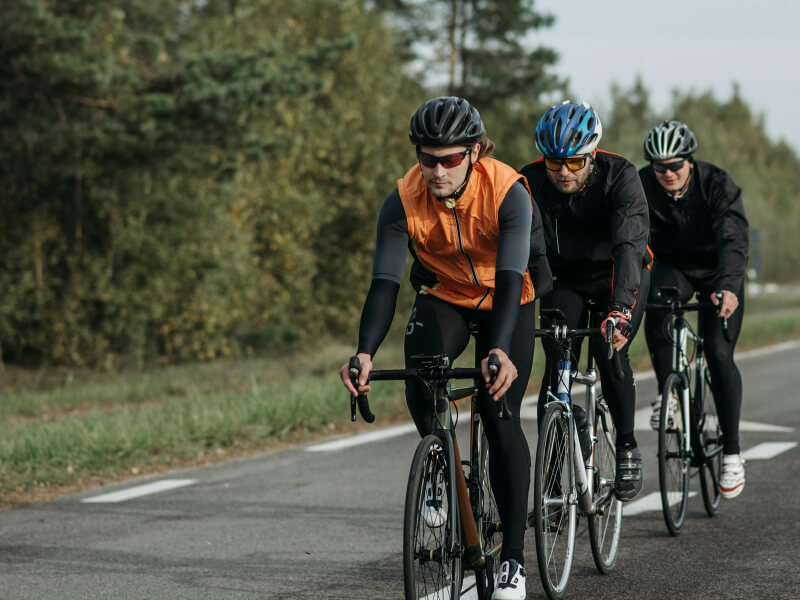 Trois cyclistes roulant en file sur route