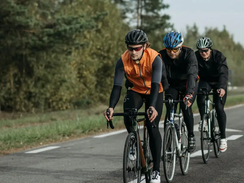 Trois cyclistes roulant en file sur route