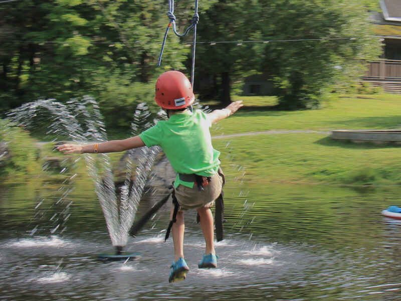Enfant en tyrolienne au-dessus d’un lac