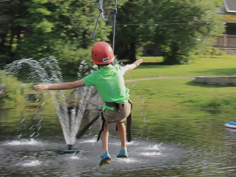 Enfant en tyrolienne au-dessus d’un lac