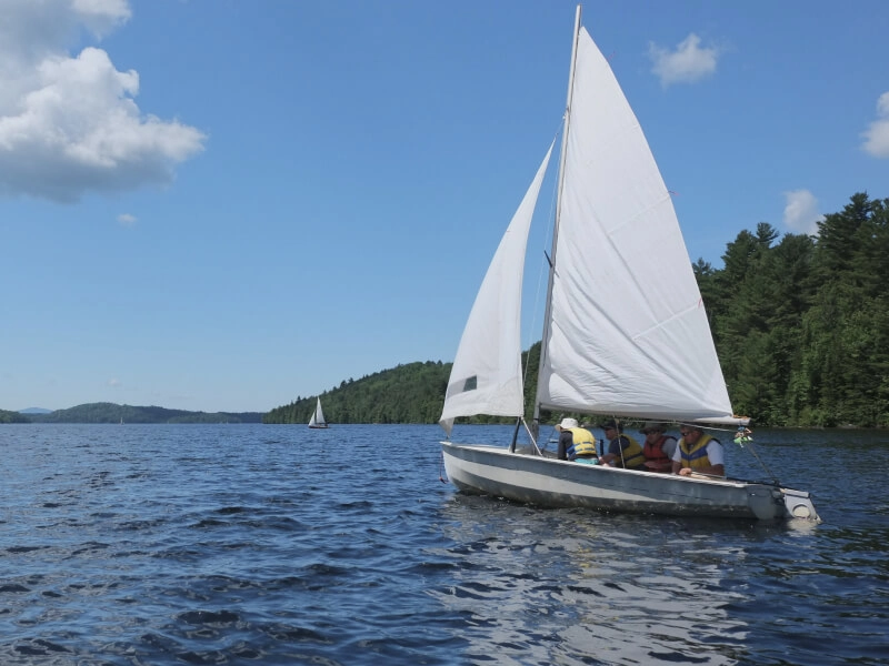 Sailboat with passengers on a lake surrounded by forest