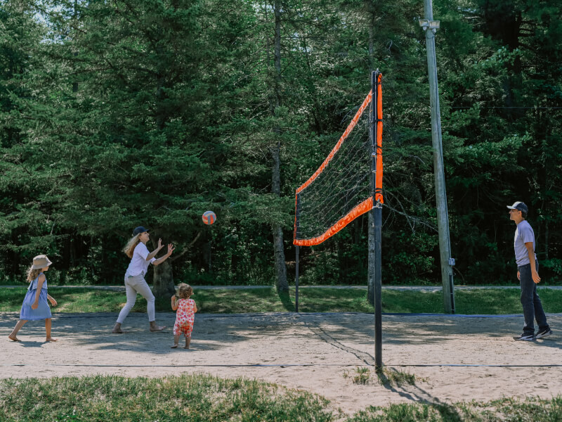 Famille jouant au volleyball sur terrain sableux