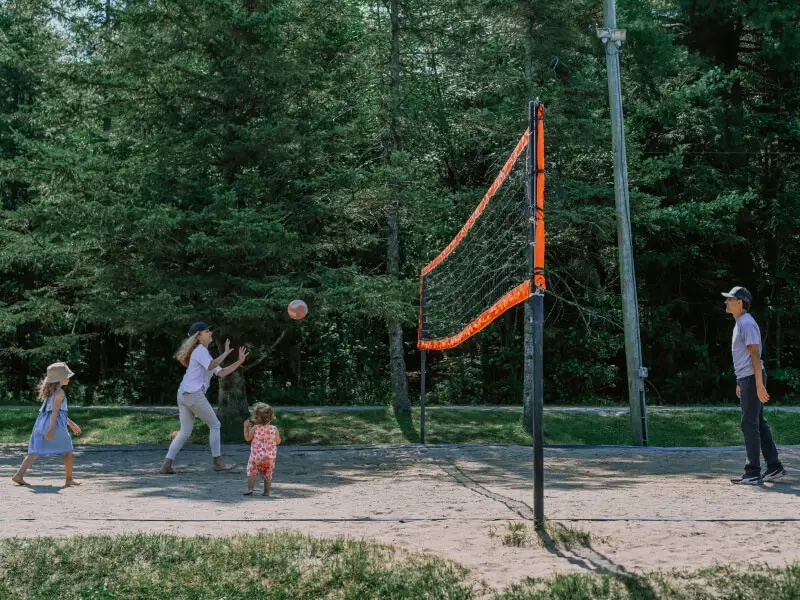 Family playing volleyball on outdoor sand court