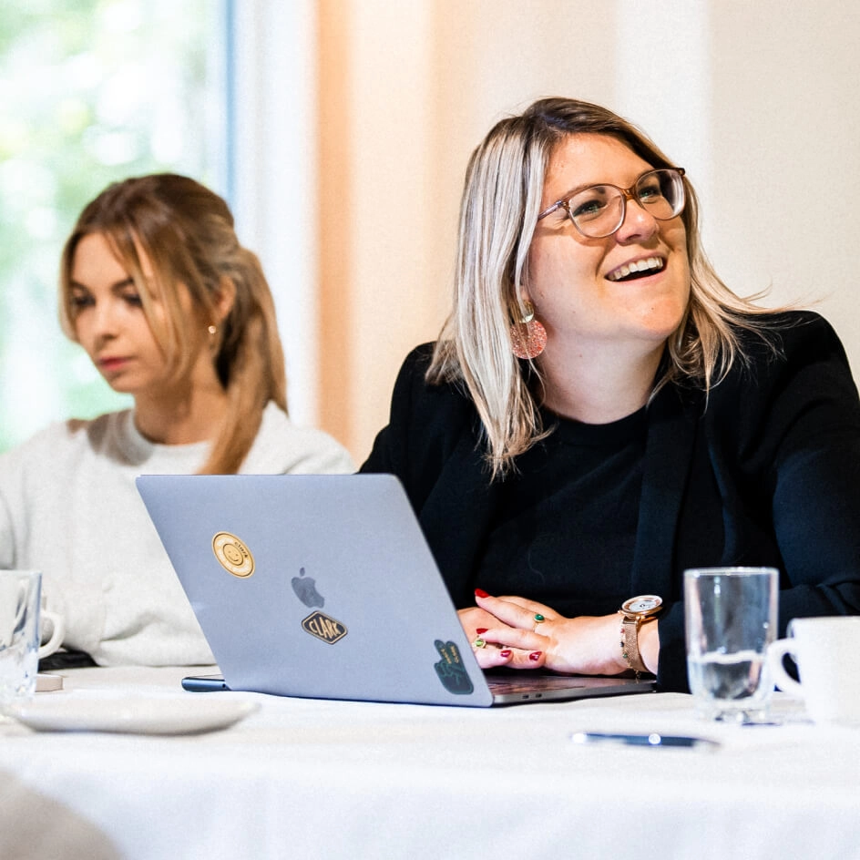 Woman smiling with laptop at meeting table