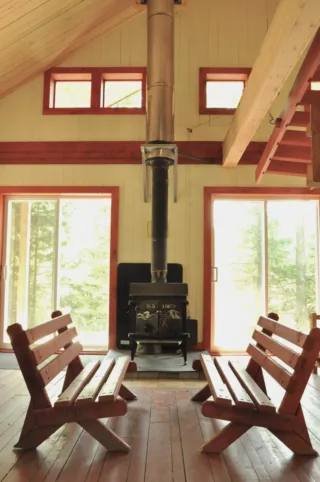 Rustic cabin interior with wood stove and benches