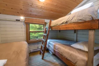 Rustic cabin bedroom with wooden bunk beds and window