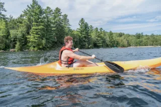 Person kayaking on forest lake wearing life jacket