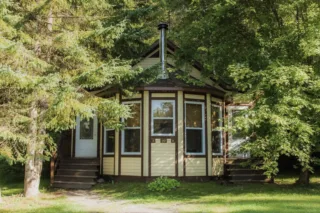 Small octagonal cabin surrounded by trees in forest