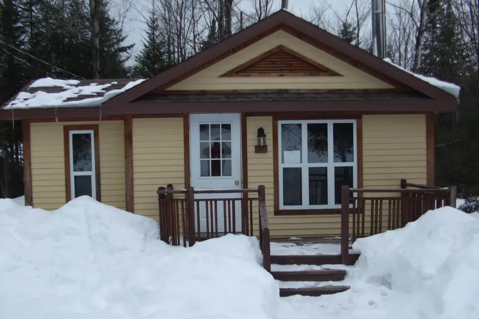 Small yellow cabin surrounded by deep snow