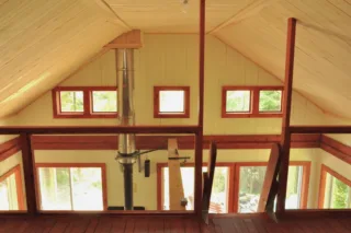 Wooden cabin loft with windows and metal stove pipe