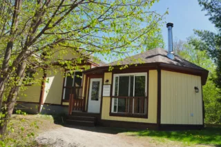 Yellow cabin with porch surrounded by trees