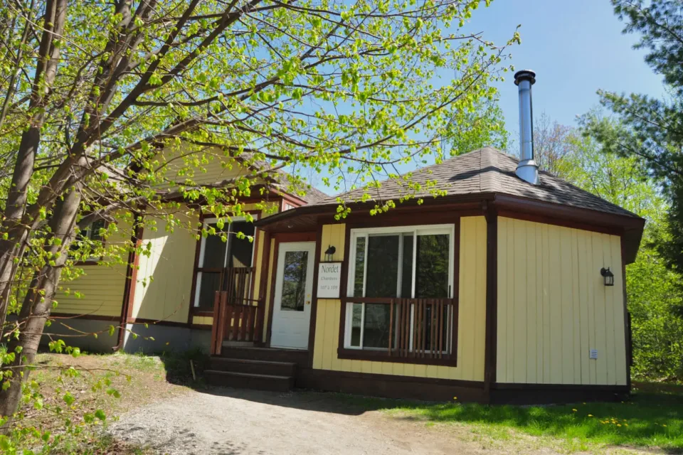 Yellow cabin with porch surrounded by trees
