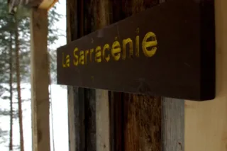 Wooden La Sarracénie sign on rustic cabin wall