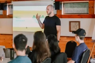 Man giving presentation to small seated audience indoors