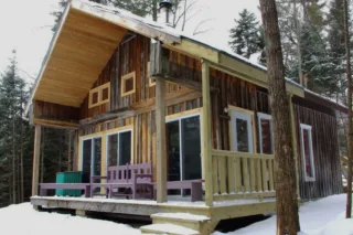 Rustic wooden cabin with porch in snowy forest