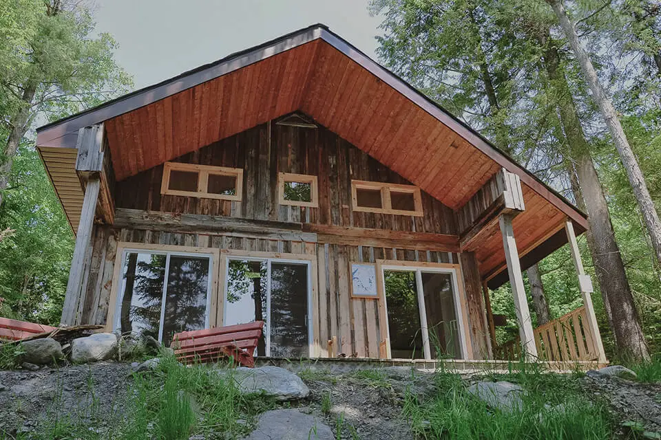 Rustic wooden cabin surrounded by trees and greenery