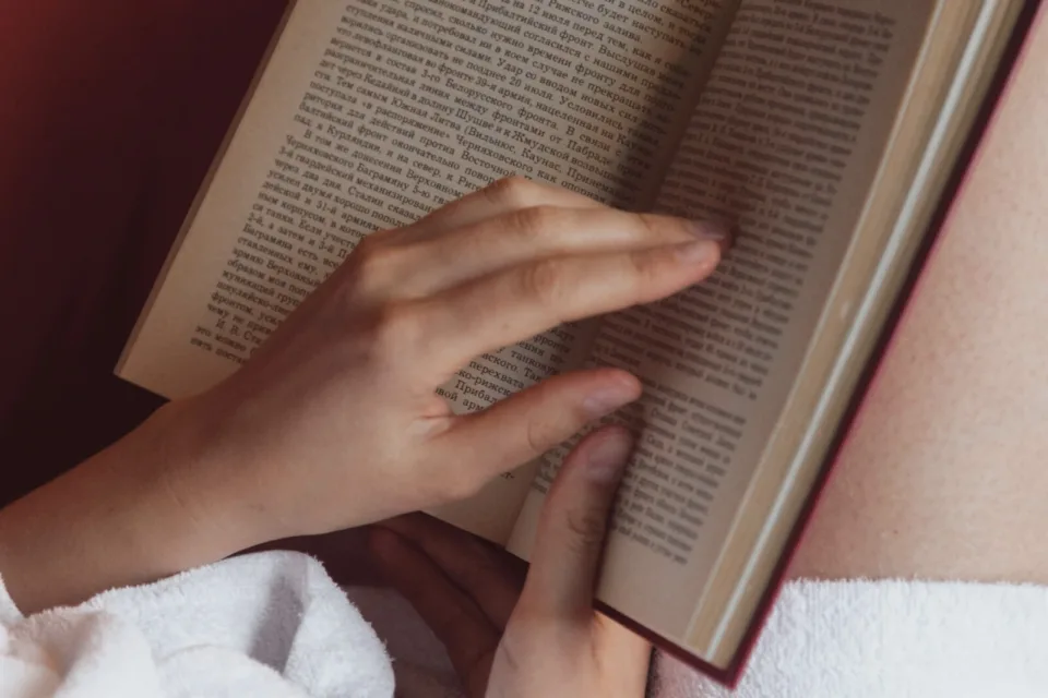 Hands reading an open book indoors