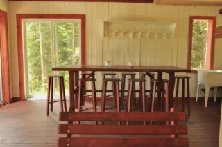Rustic wooden dining room with stools and forest view