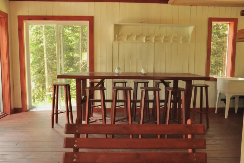 Rustic wooden dining room with stools and forest view